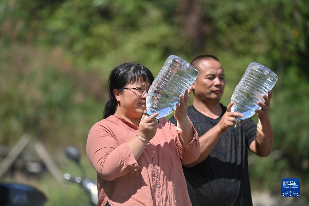 楊寧（左）在查看村民剛剛采集的水樣，為山泉水引水工程做準(zhǔn)備（10月8日攝）。新華社記者 黃孝邦 攝